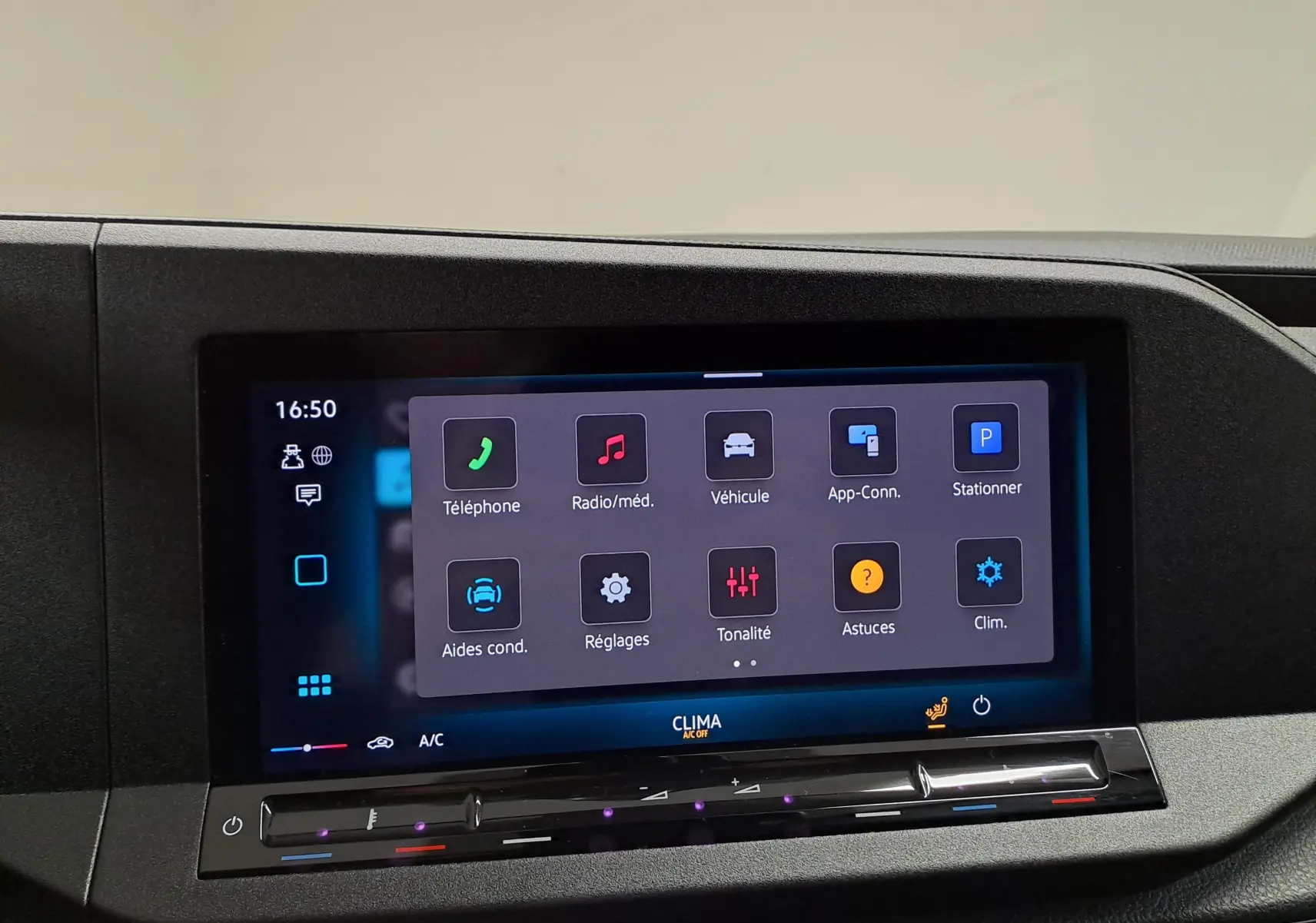 Écran tactile central du tableau de bord du Volkswagen Caddy blanc, affichant les menus de contrôle multimédia et climatisation.