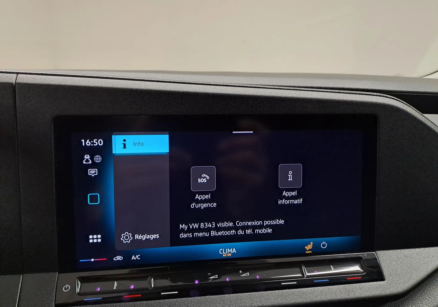 Écran tactile central du tableau de bord du Volkswagen Caddy blanc, affichant les options d'appel d'urgence et réglages.