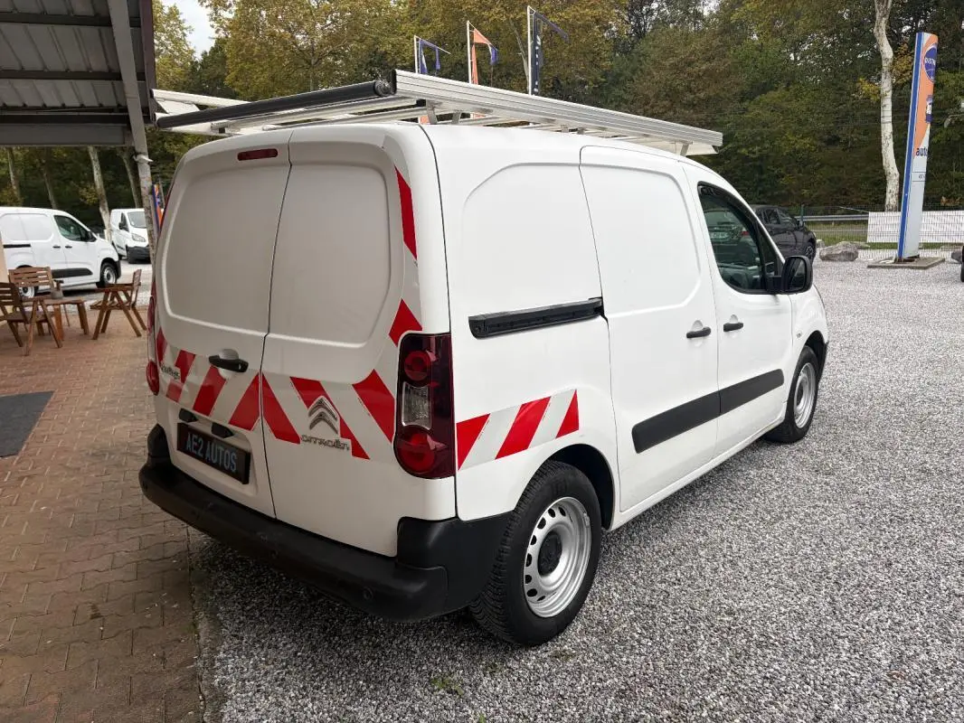 Vue 3/4 arrière droite d’un Citroën Berlingo blanc 2018 avec marquages rouges réfléchissants et galerie sur le toit.