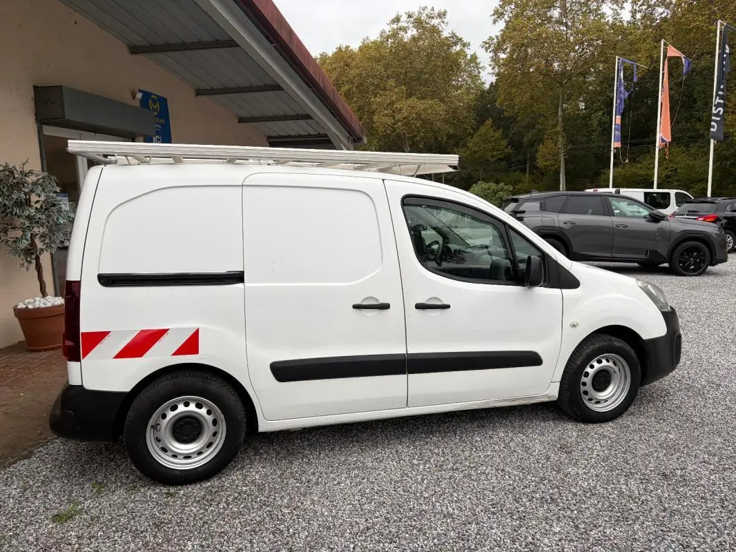 Vue de profil côté gauche d’un Citroën Berlingo blanc fourgon 2018 avec marquages réfléchissants rouges à l’arrière et galerie sur le toit.