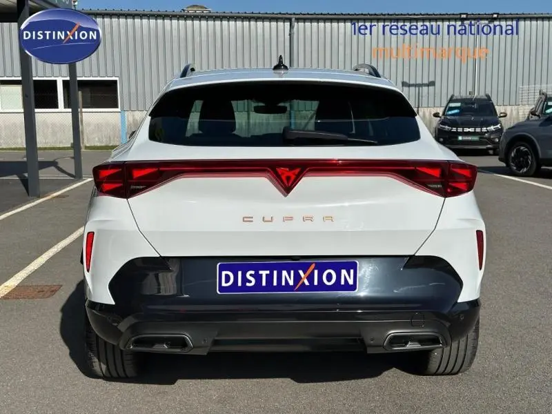 Vue arrière d'une CUPRA Formentor blanc Nevada métallisé avec feux arrière rouges et double sortie d'échappement.