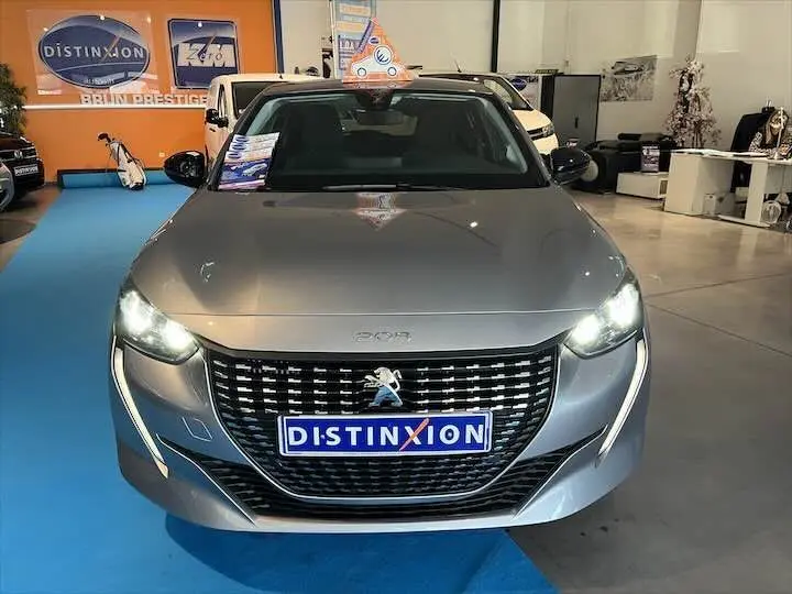 Vue avant d'une Peugeot 208 gris Artense métal avec phares allumés et plaque Distinxion en concession