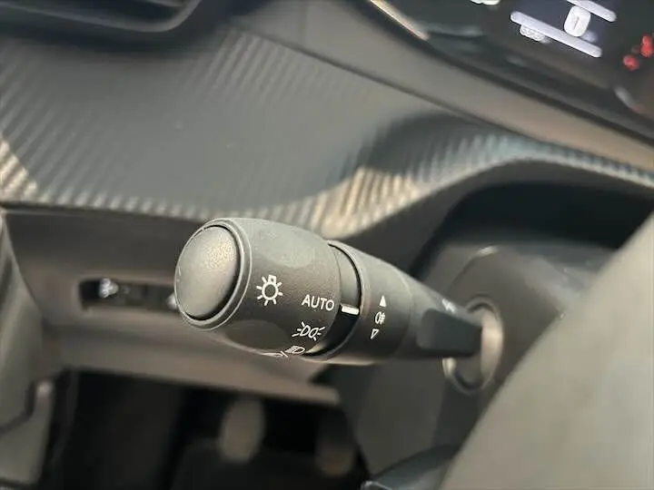 Gros plan sur la commande des feux du tableau de bord intérieur gris noir de la Peugeot 208 1.2 100 CH S&S STYLE.