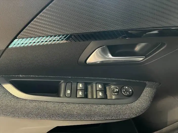 Détail de la porte côté gauche de la Peugeot 208 gris Artense métal, montrant les commandes des vitres et le bouton de réglage des rétroviseurs.