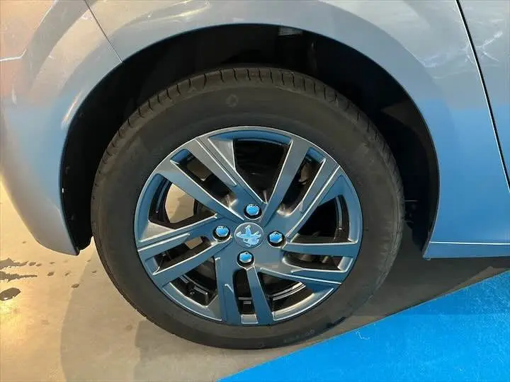 Gros plan sur la roue avant gauche d'une Peugeot 208 gris Artense métal avec jante alliage noire brillante.