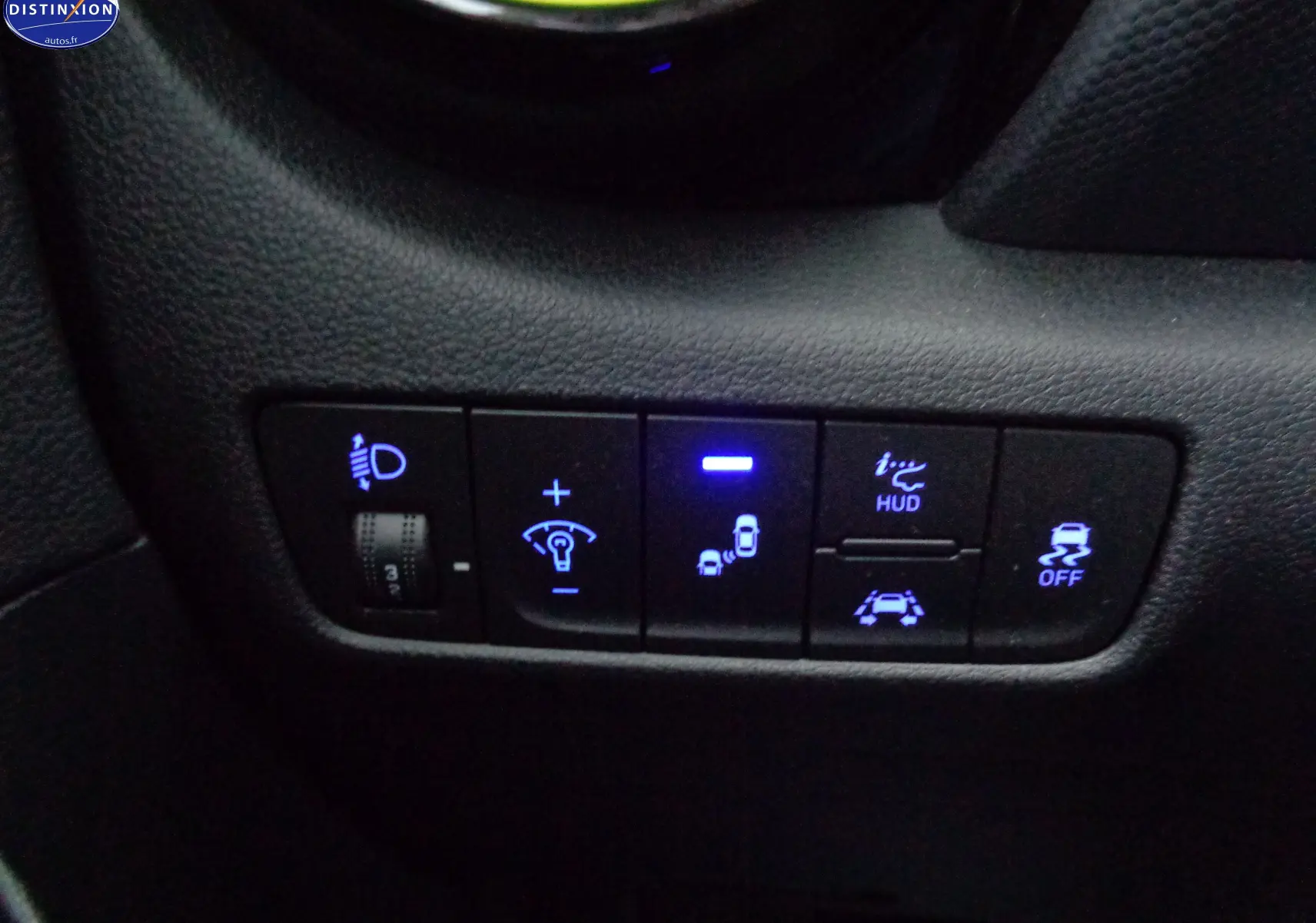 Gros plan sur les commandes éclairage et aides à la conduite du Hyundai Kona 1.6 CRDI jaune Acid Yellow, tableau de bord côté gauche.