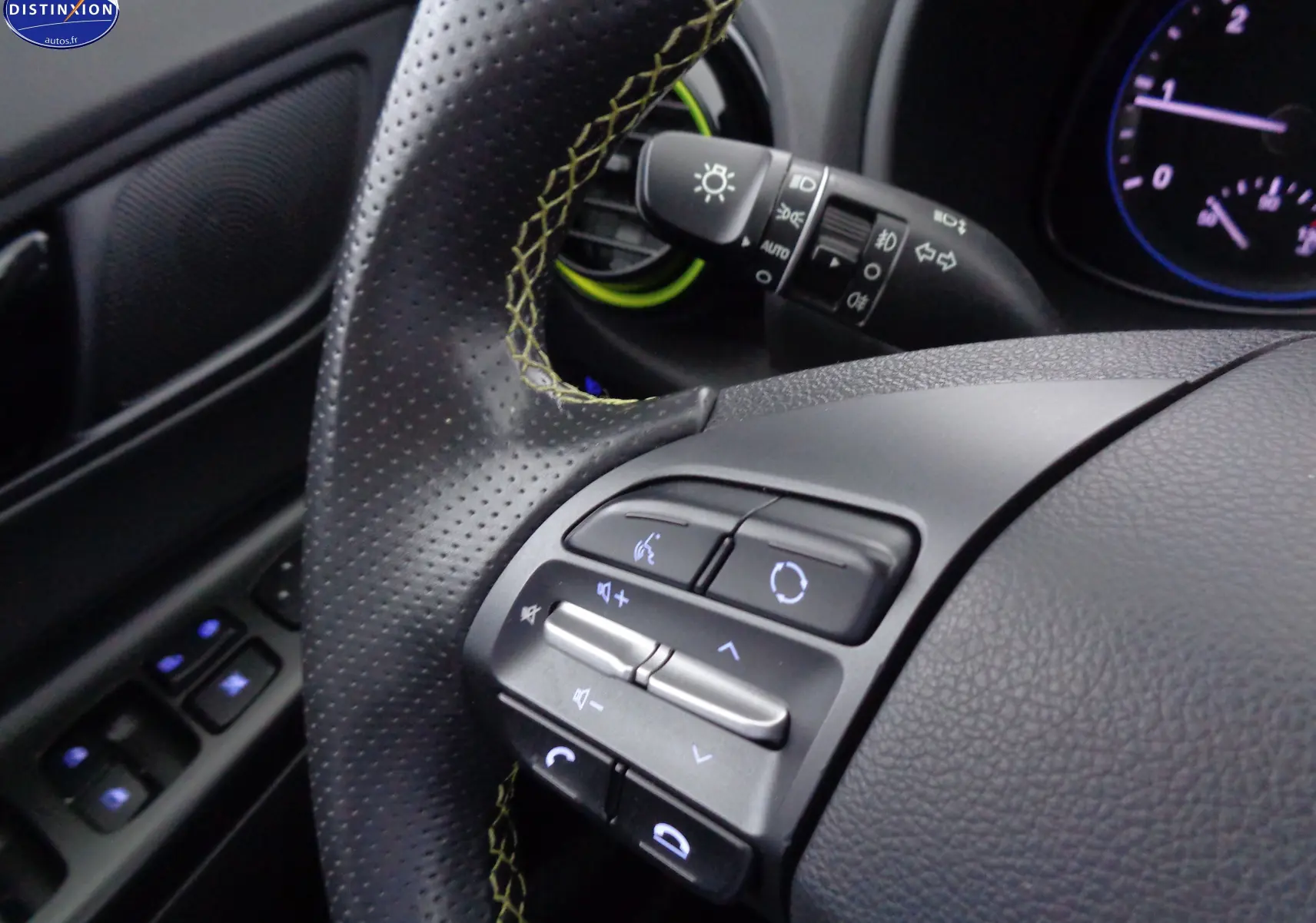 Gros plan sur le volant noir perforé avec surpiqûres jaunes du Hyundai Kona 2019, montrant les commandes audio et téléphone.