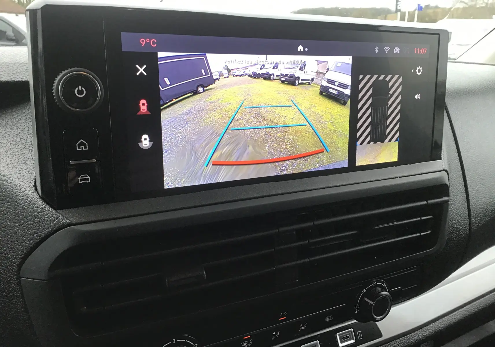 Écran tactile intérieur montrant la caméra de recul du FIAT Scudo Fourgon blanc, avec lignes de guidage colorées.