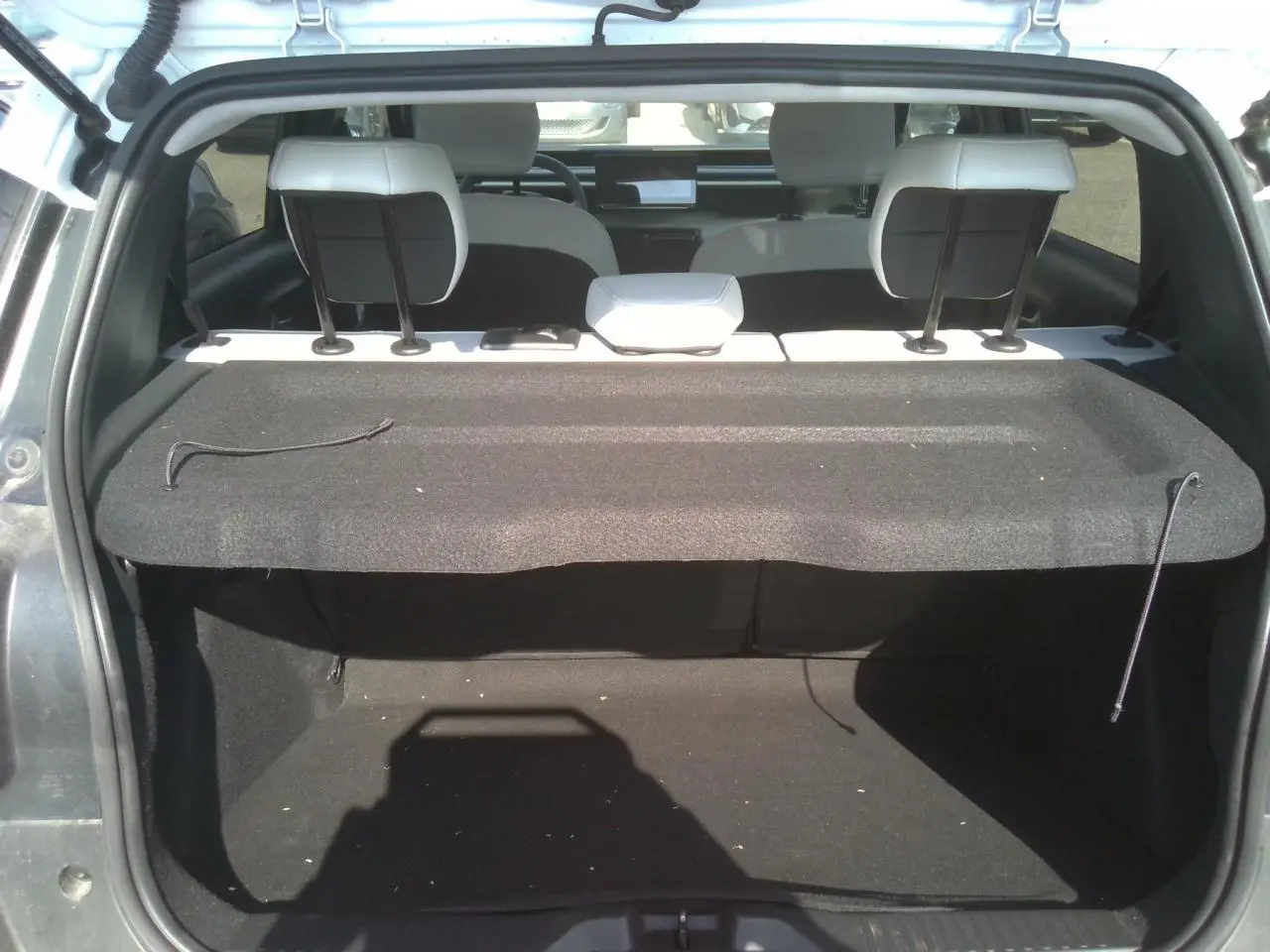 Coffre ouvert vu de l'arrière d'une Citroën C3 2025 noir Perla avec plage arrière et sièges blancs visibles.