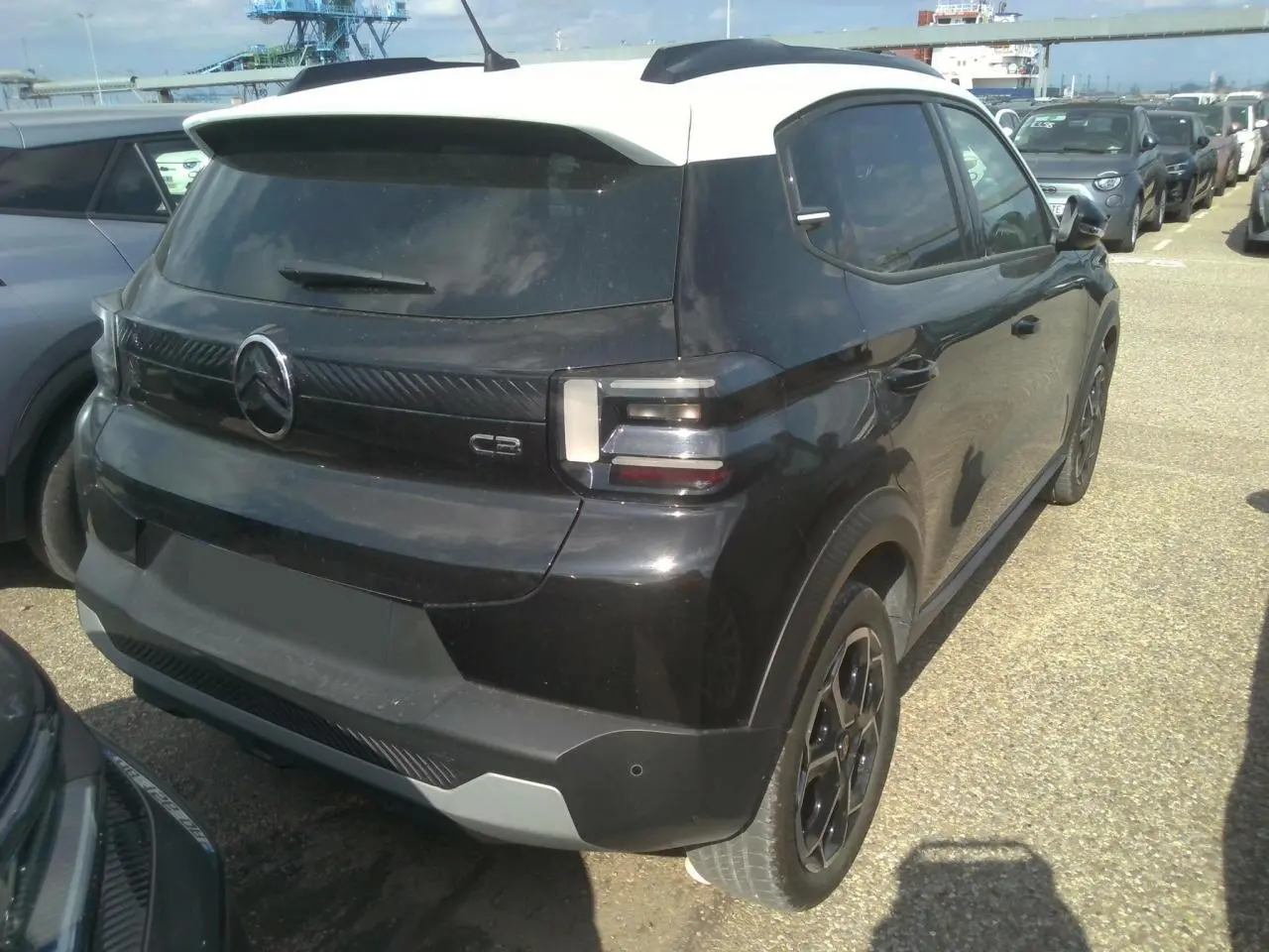 Vue 3/4 arrière droite d'une Citroën C3 2025 noire Perla Nera avec toit blanc Opale et jantes alliage noires.