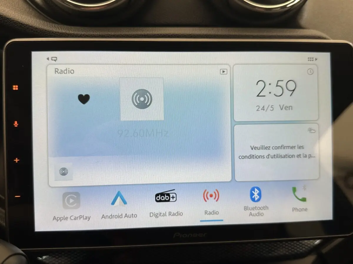Vue intérieure centrée sur l’écran tactile multimédia Pioneer affichant la radio, dans une Aixam Ambition 0.5 City GTO blanche.
