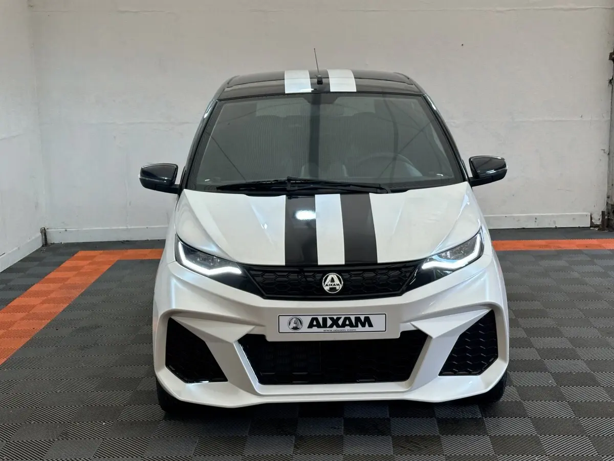 Vue avant d'une Aixam Ambition 0.5 City GTO blanche avec bandes noires et rétroviseur caméra côté gauche.
