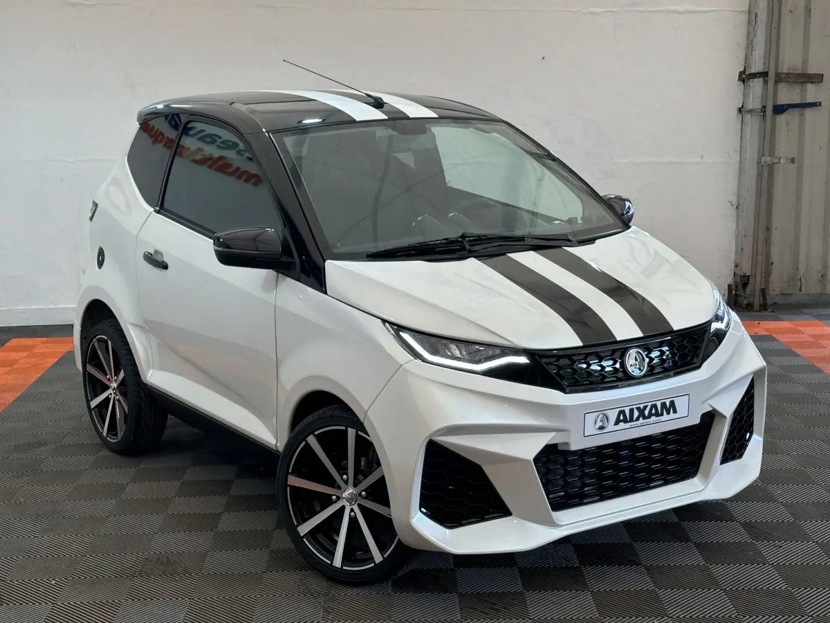 Vue 3/4 avant d'une Aixam Ambition 0.5 City GTO blanche avec toit noir et bandes noires sur le capot.