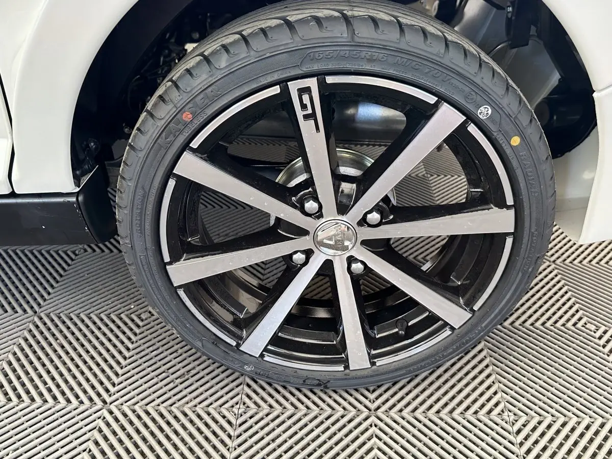 Gros plan sur la roue avant droite de l'AIXAM AMBITION 0.5 CITY GTO blanche, jante noire et argentée au design moderne.