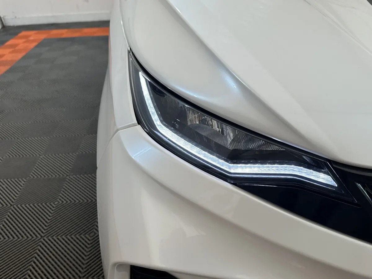 Gros plan sur le phare avant gauche blanc de l'AIXAM AMBITION 0.5 CITY GTO 2026 avec éclairage LED allumé.