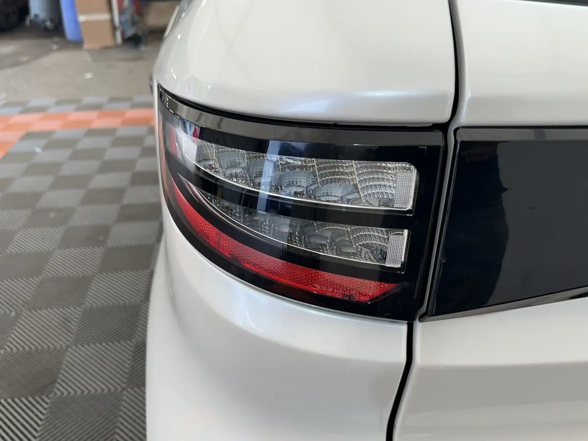 Gros plan sur le feu arrière droit blanc de l'AIXAM AMBITION 0.5 CITY GTO 2026 avec détails noirs et rouge.