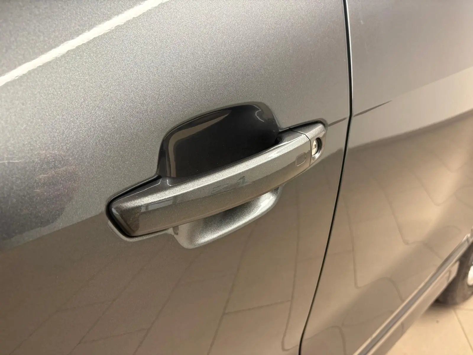 Gros plan sur la poignée de porte côté droit de l'Audi Q2 35 TFSI gris Daytona avec peinture métallisée.