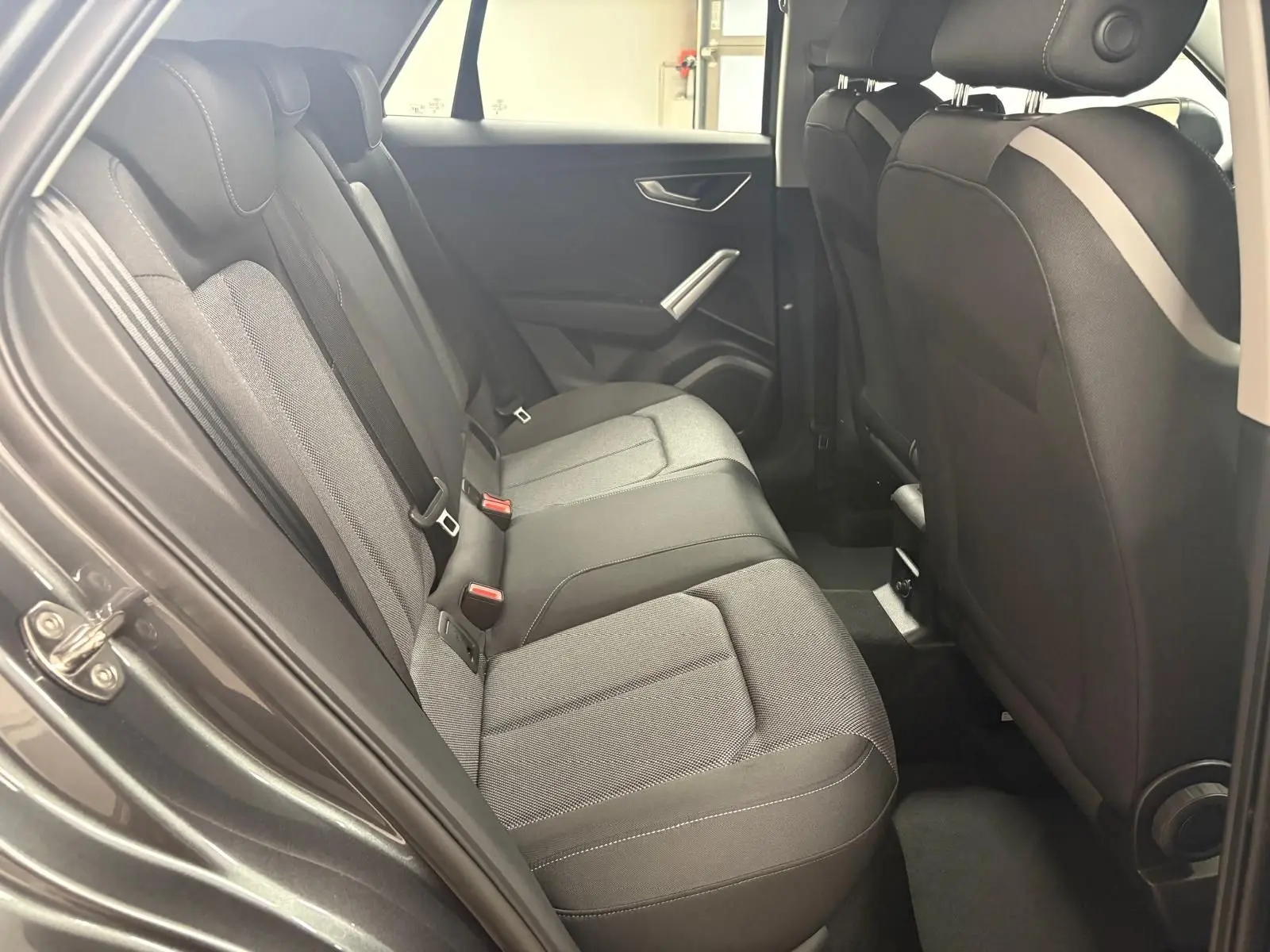 Vue intérieure côté gauche des sièges arrière gris foncé de l'Audi Q2 35 TFSI S Line 2026 avec porte ouverte.