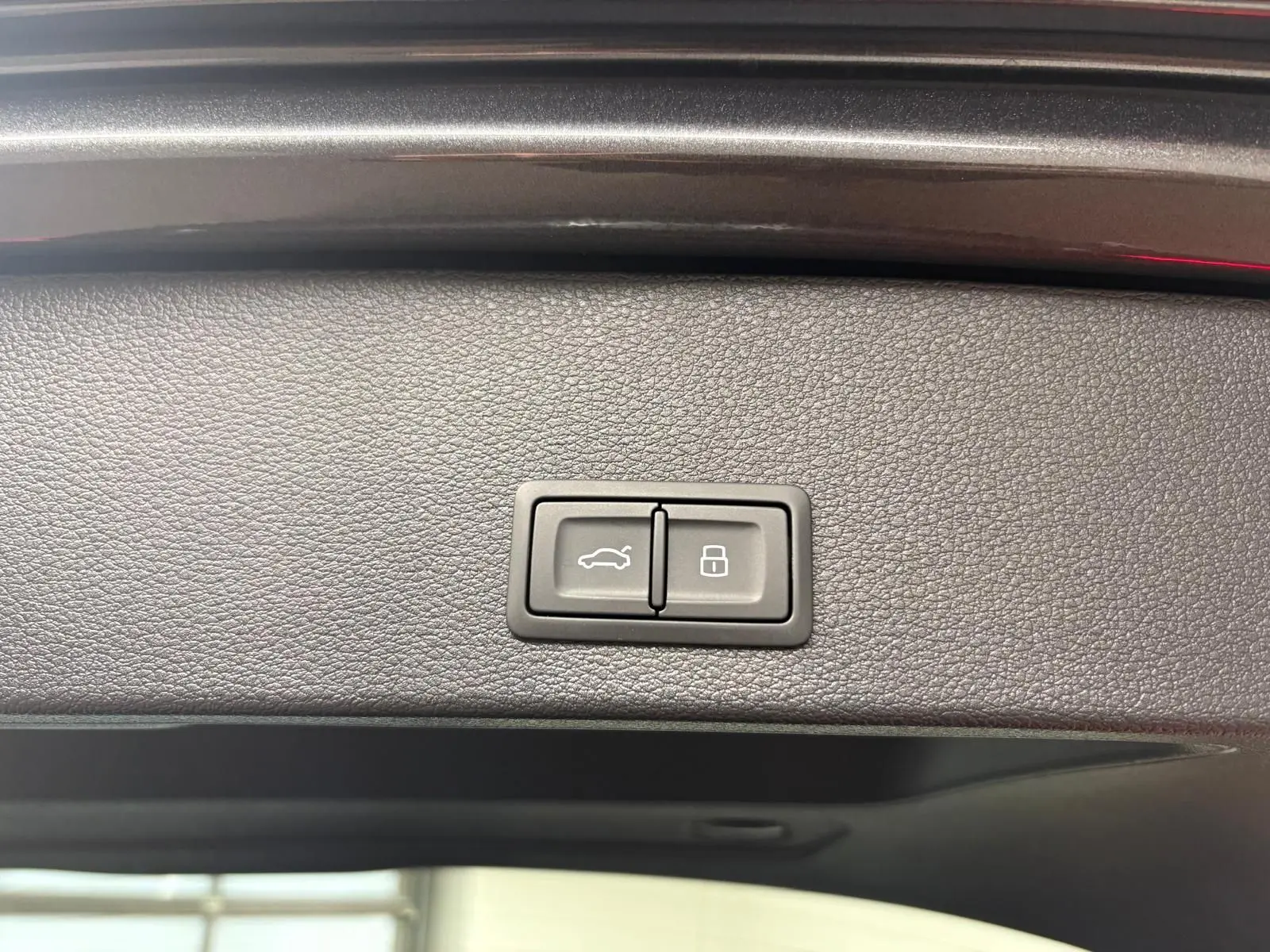 Boutons du hayon électrique et verrouillage intégrés sur la garniture intérieure du coffre d'un Audi Q2 gris Daytona 2026.