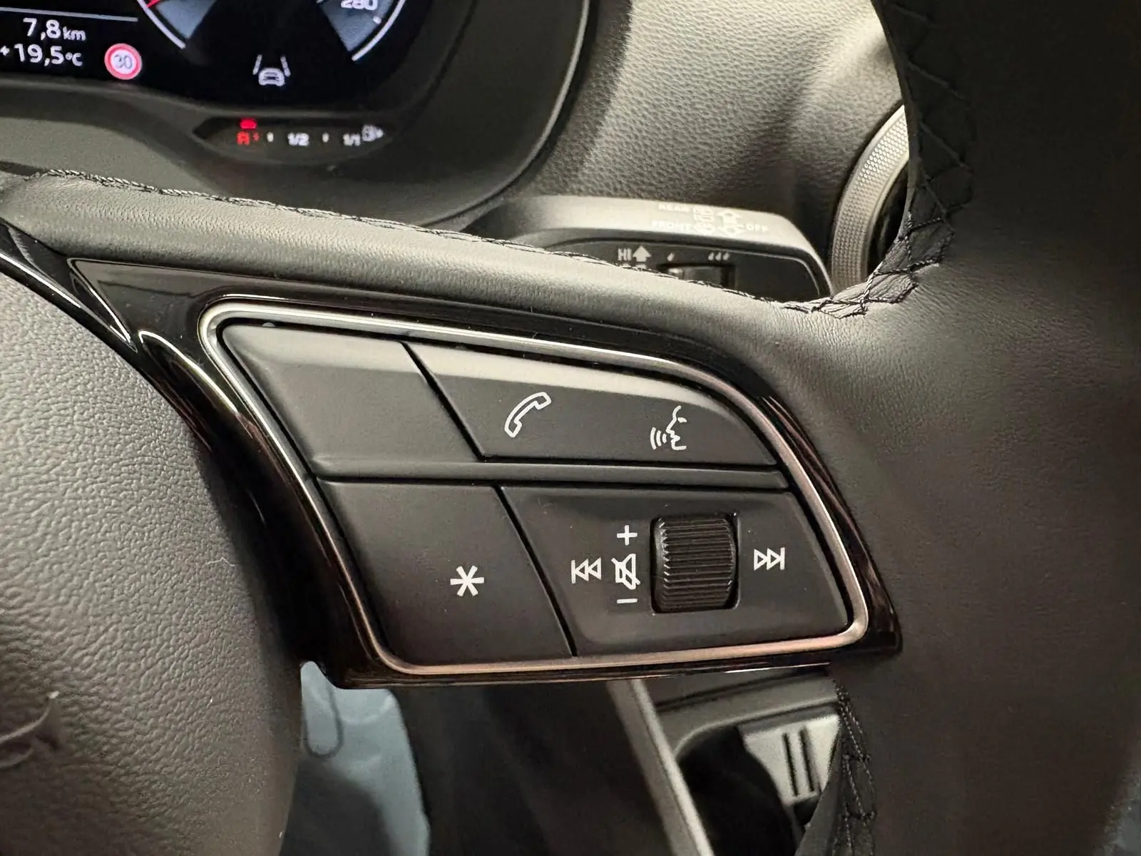 Gros plan sur les commandes du volant de l'Audi Q2 35 TFSI S Line 2026 en Gris Daytona, avec boutons multifonctions visibles.