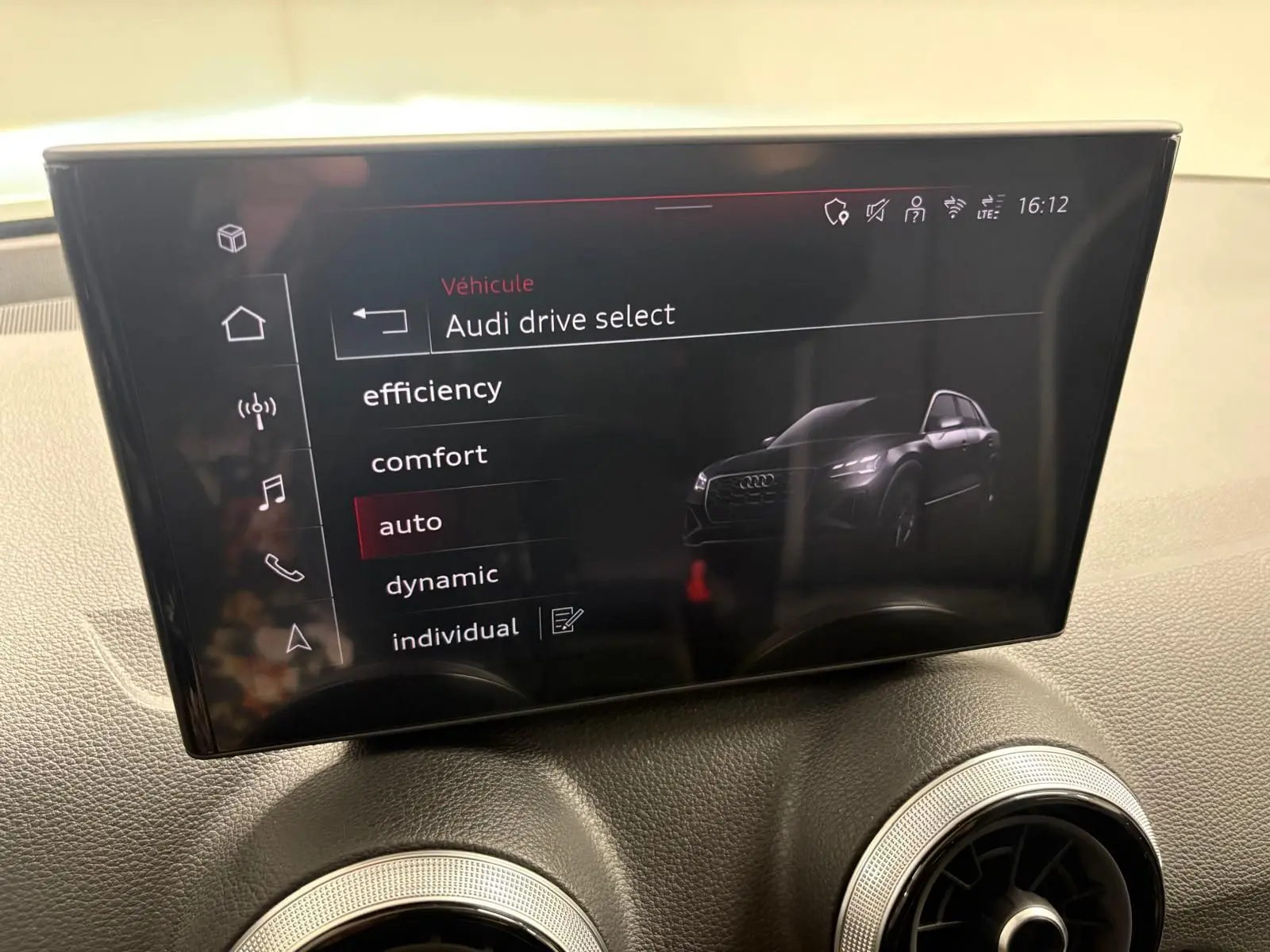 Écran central intérieur montrant le menu Audi drive select avec image stylisée du Q2 en vue 3/4 avant.