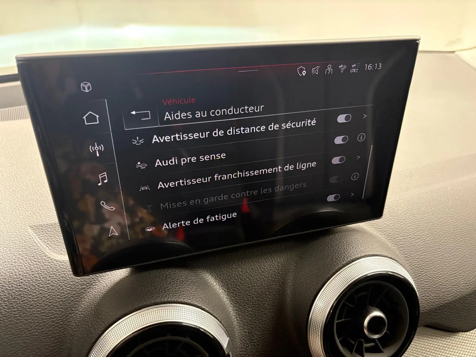 Écran central de l’Audi Q2 35 TFSI 150 S tronic 7 S line 2026 affichant les aides à la conduite, intérieur noir.