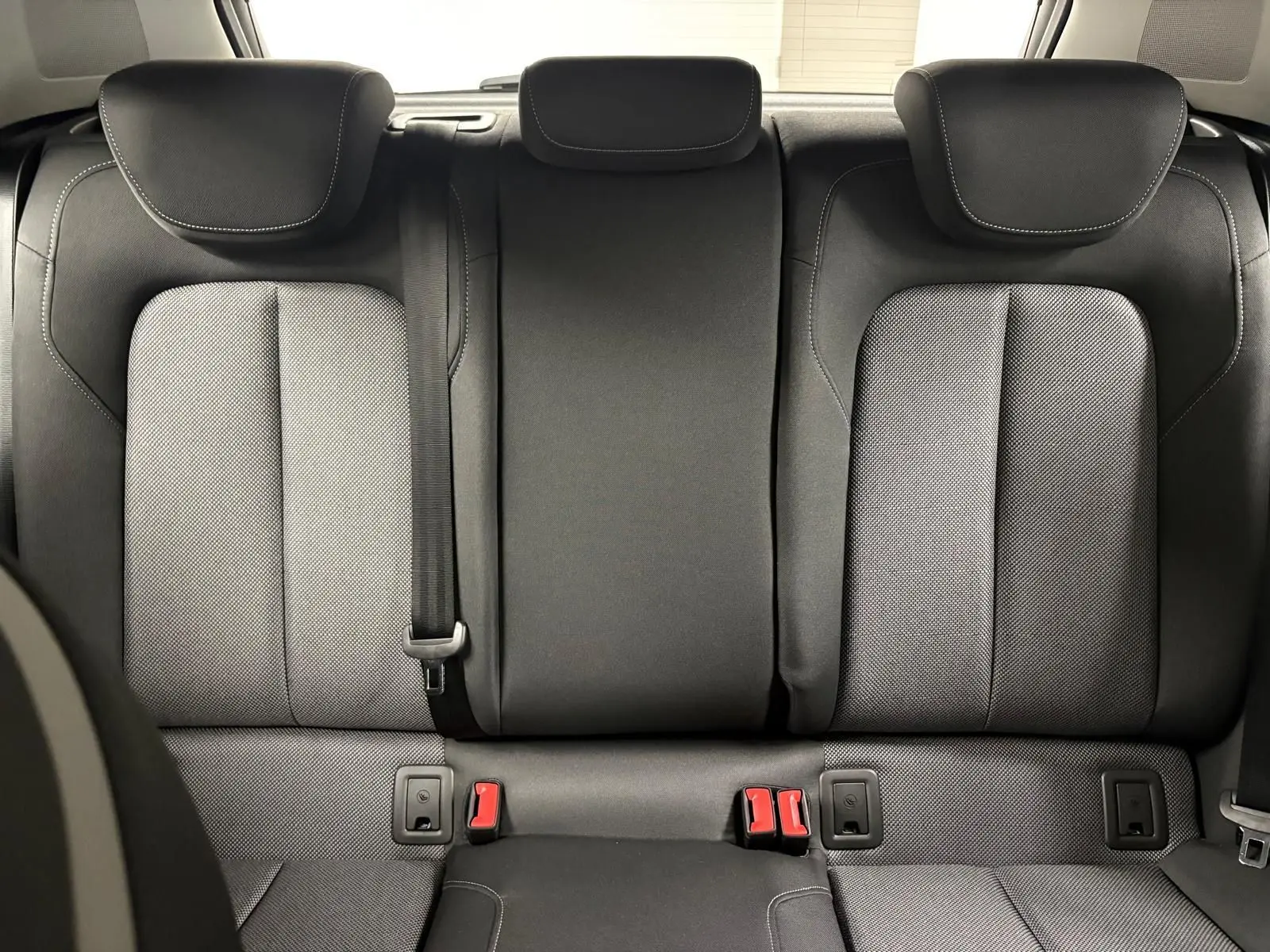 Vue rapprochée des sièges arrière noirs de l’Audi Q2 35 TFSI S line 2026, soulignant les appuie-têtes et ceintures.