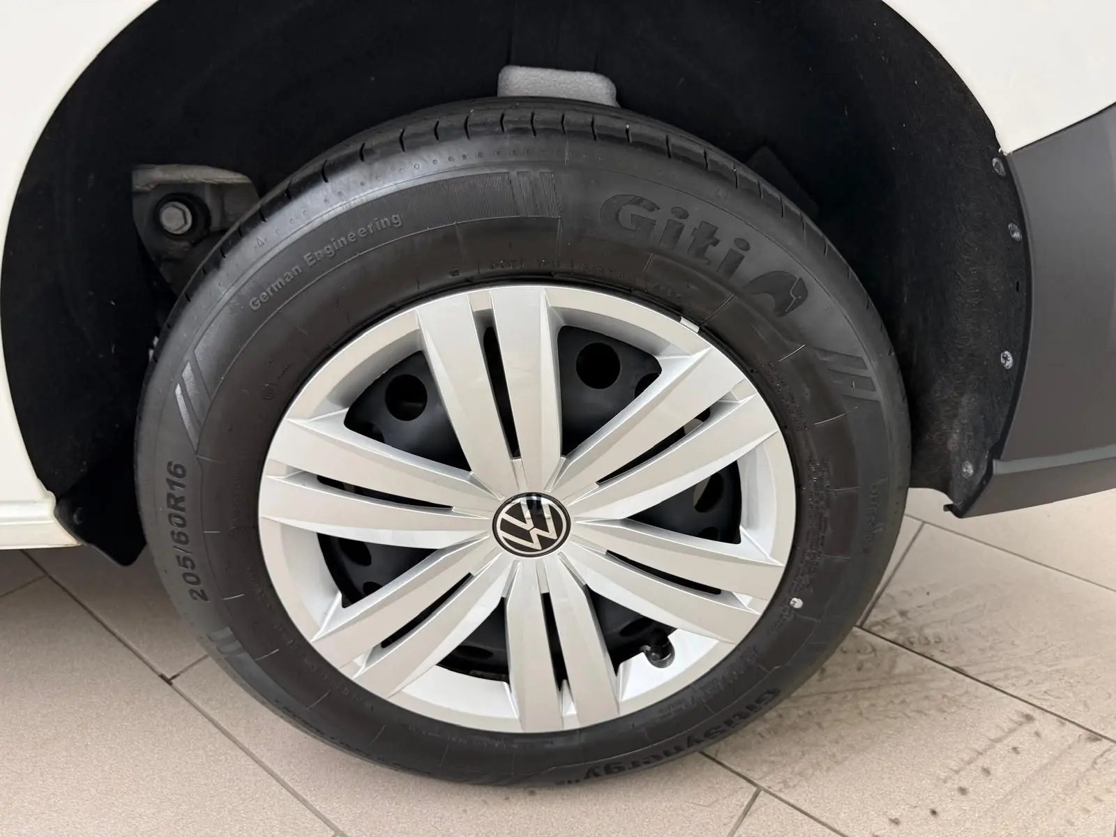 Gros plan sur la roue avant gauche blanche du Volkswagen Caddy 2.0 TDI 122 DSG7 Business 2025.