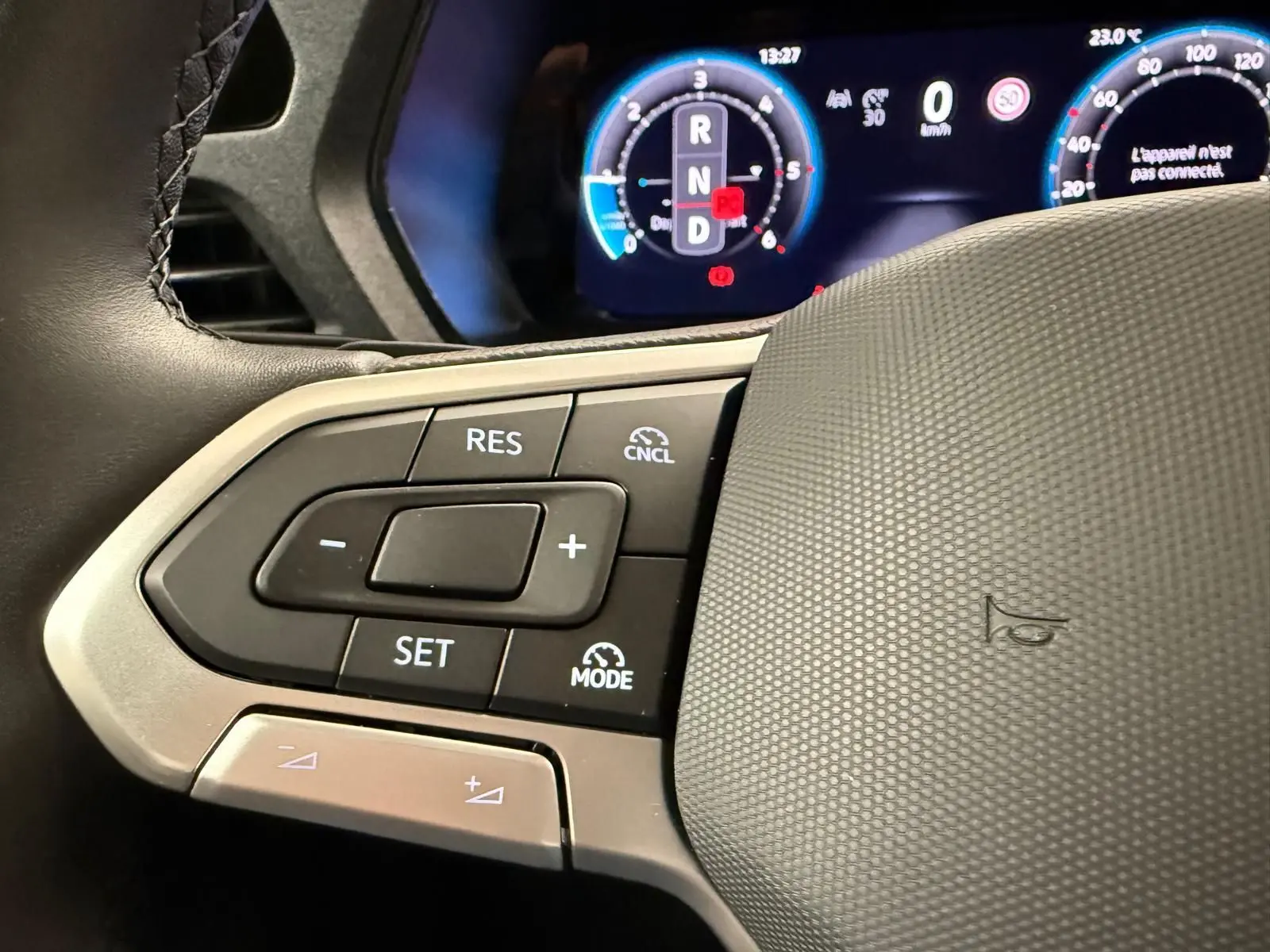 Gros plan sur les commandes au volant à gauche du Volkswagen Caddy blanc 2025 avec affichage numérique en arrière-plan.