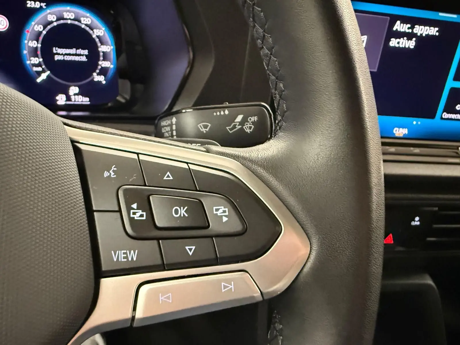 Gros plan sur les commandes multifonctions à gauche du volant cuir du Volkswagen Caddy 2025 avec tableau de bord digital en arrière-plan.