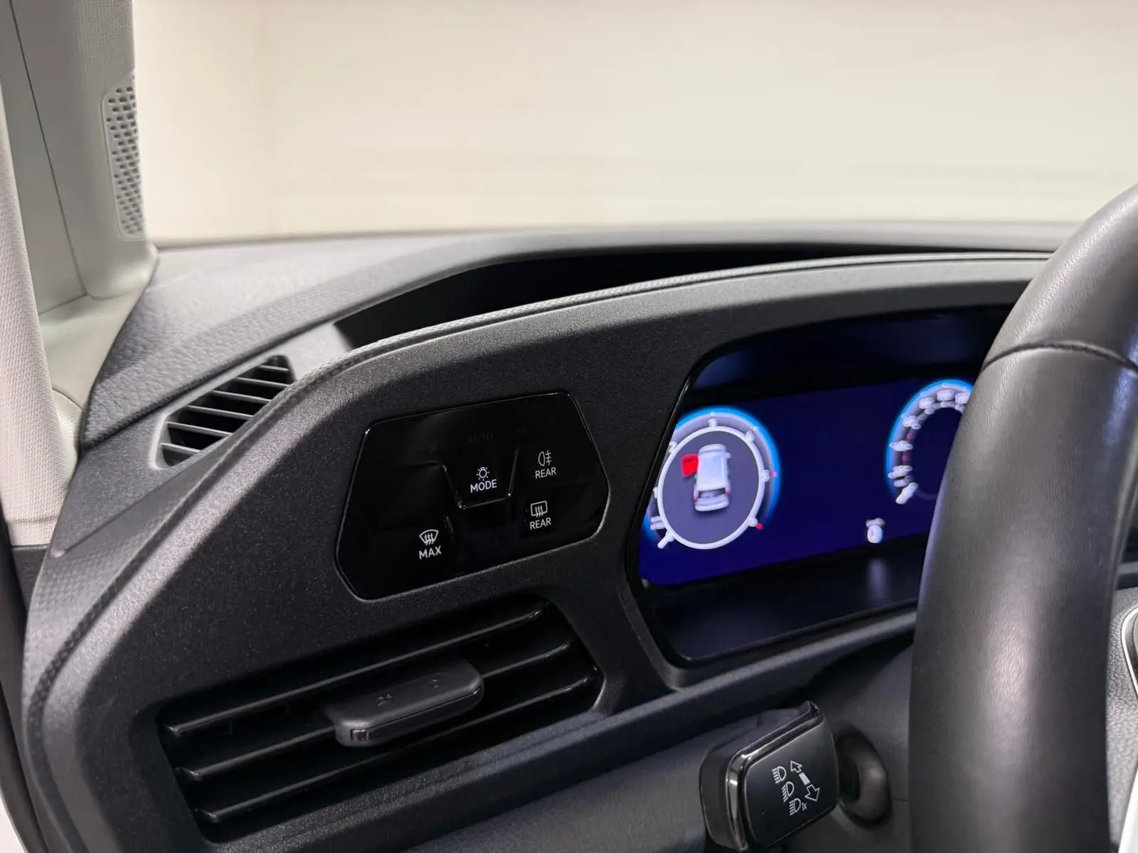 Vue intérieure du tableau de bord côté gauche du Volkswagen Caddy 2025 avec écran digital et commandes d'éclairage.