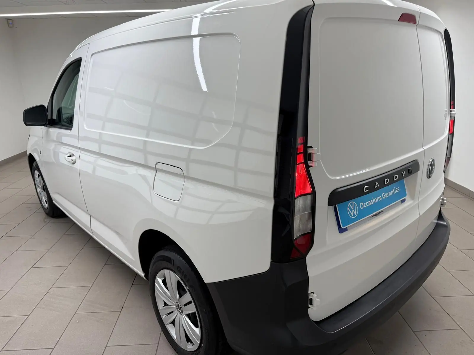 Vue 3/4 arrière droite du Volkswagen Caddy blanc Candy, avec feux arrière verticaux et pare-chocs noir mat.