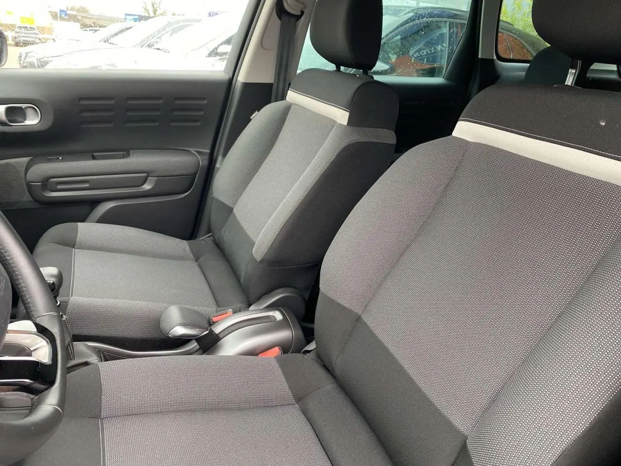 Vue intérieure côté gauche des sièges avant gris du Citroën C3 Aircross 2020 avec détails tissu et accoudoir central.
