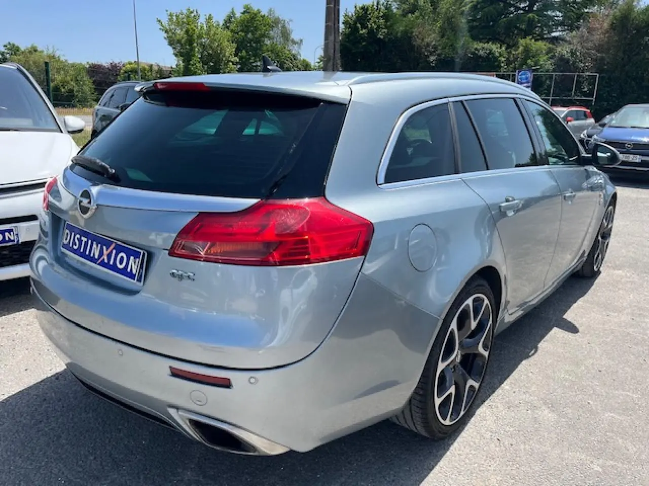 Vue 3/4 arrière droite d'une Opel Insignia Sports Tourer gris clair avec jantes alliage 20'' et double sortie d'échappement chromée.