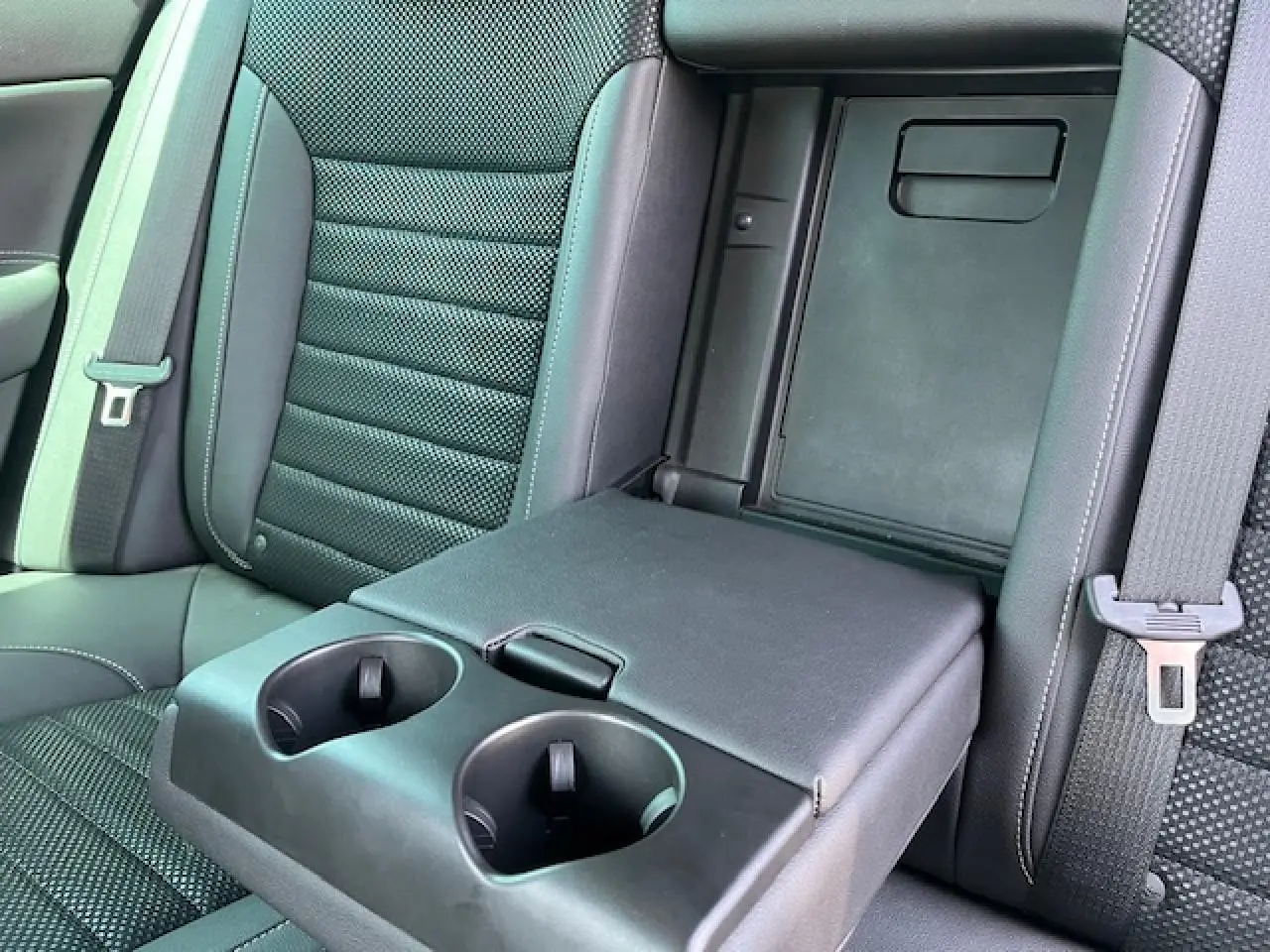 Détail de l'accoudoir arrière noir avec porte-gobelets déployé sur la banquette arrière de l'Opel Insignia Sports Tourer.