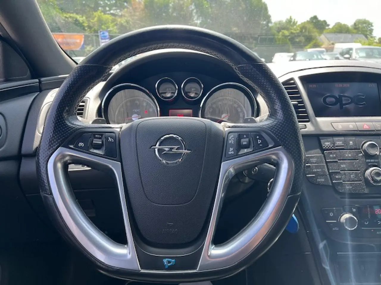 Vue intérieure centrée sur le volant noir perforé de l’Opel Insignia Sports Tourer avec tableau de bord et écran OPC.