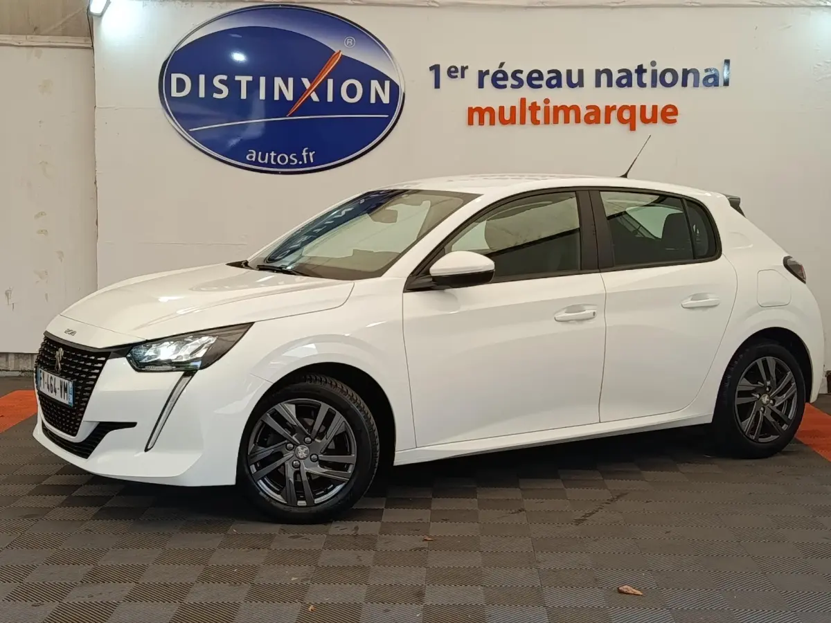 Peugeot 208 blanc vue de profil côté gauche, avec feux LED et jantes alliage sombres en intérieur showroom.