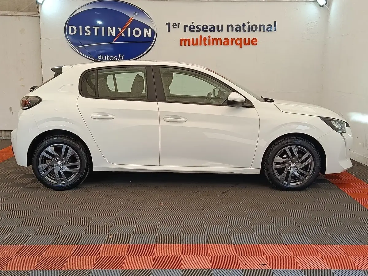 Profil latéral droit d'une Peugeot 208 blanche de 2021, avec jantes alliage et rétroviseurs électriques rabattables.