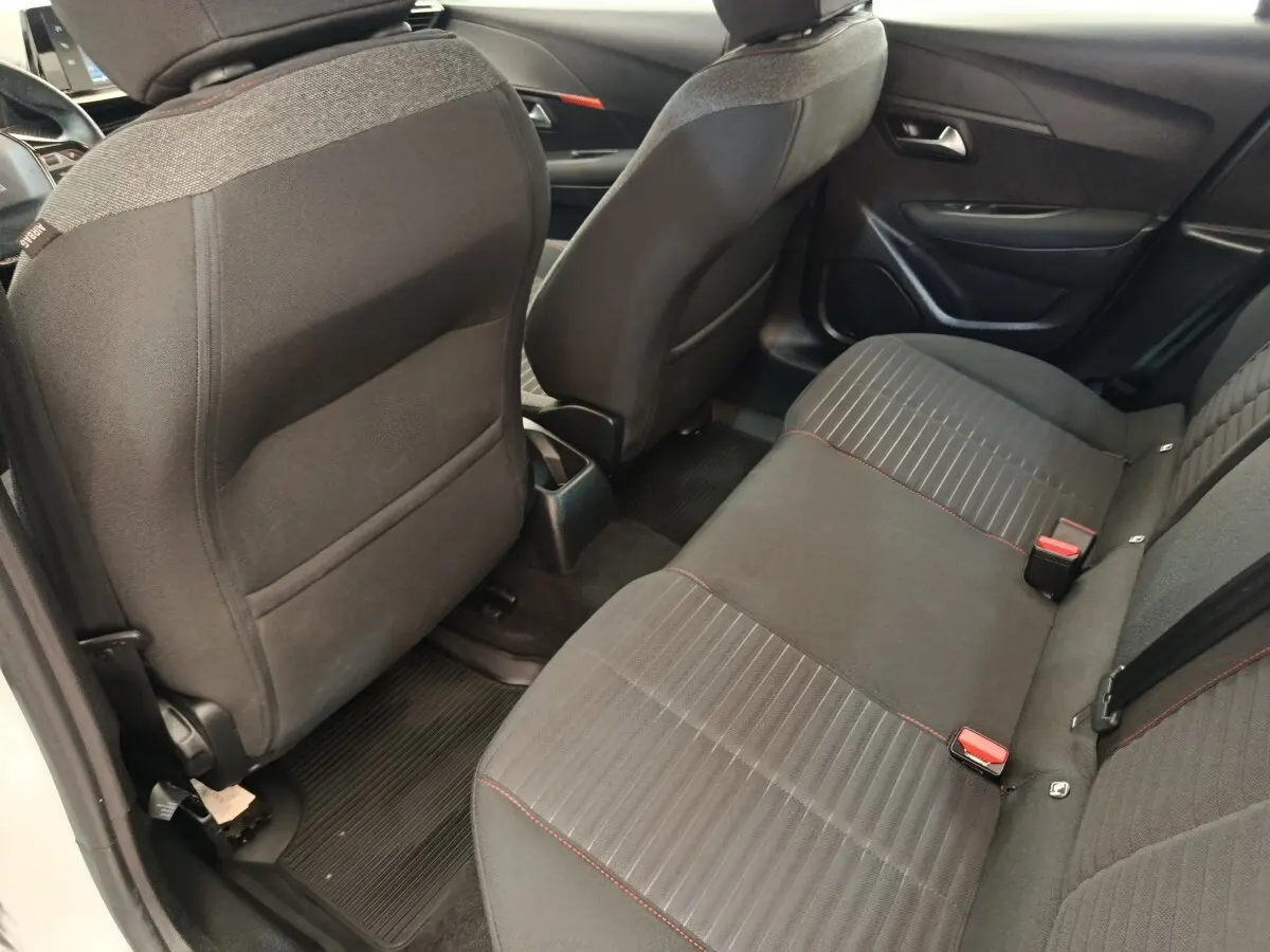 Vue arrière des sièges arrière noirs avec surpiqûres rouges dans une Peugeot 208 PureTech 75 S&S Active Business blanche.