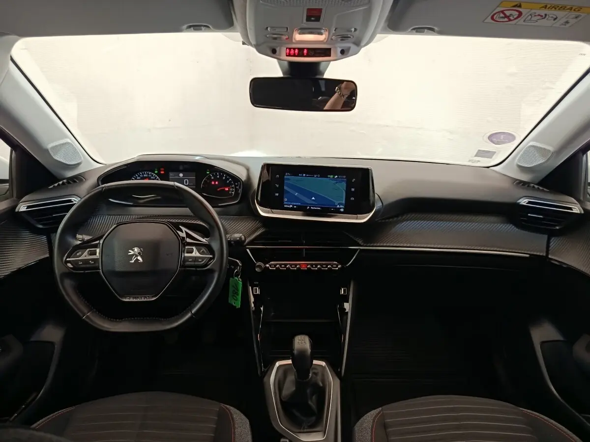 Vue intérieure avant de la Peugeot 208 blanche 2021, volant cuir multifonctions et écran tactile de navigation central.