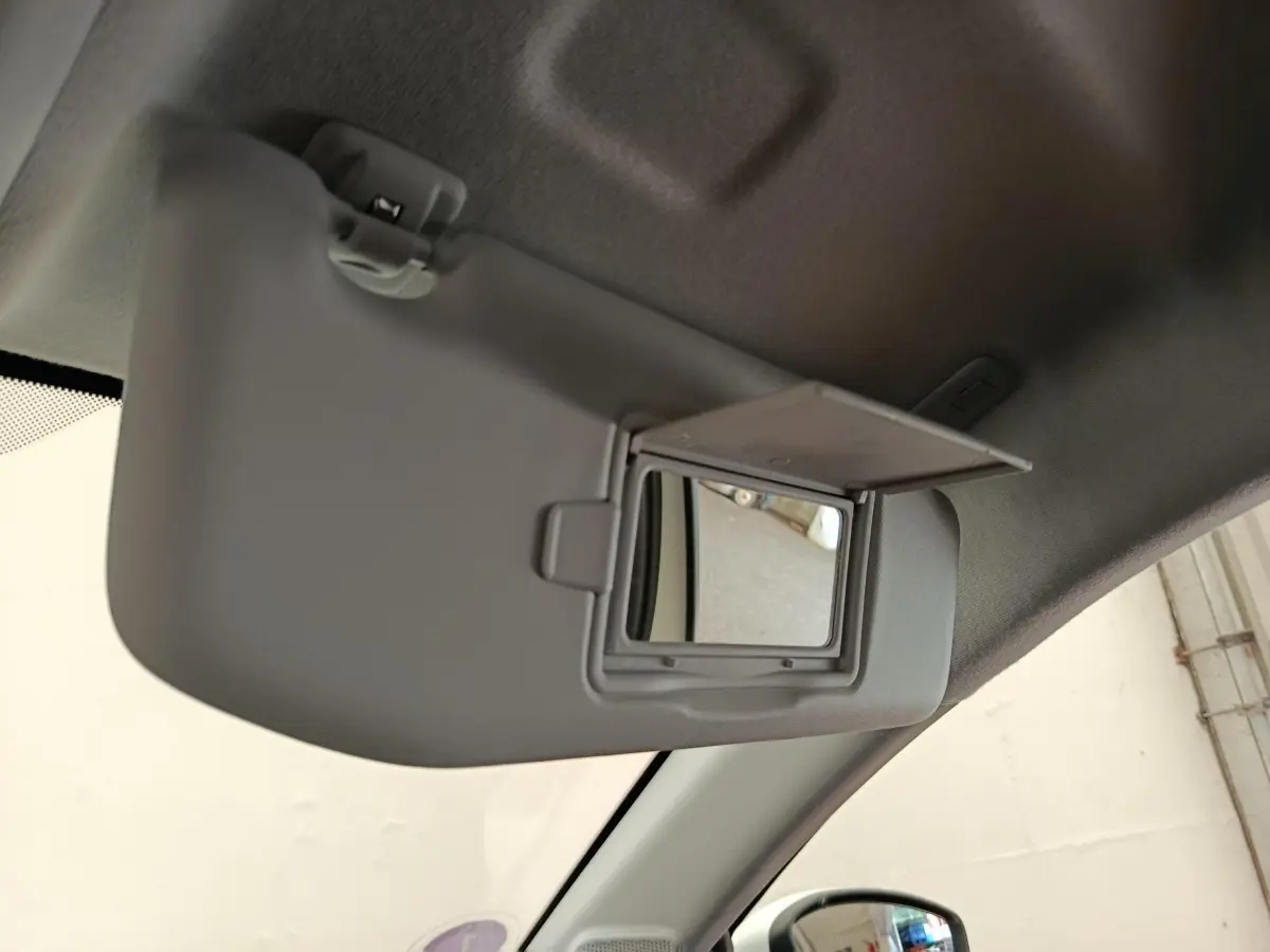 Vue intérieure du pare-soleil côté conducteur gris avec miroir de courtoisie ouvert dans une Peugeot 208 blanche.