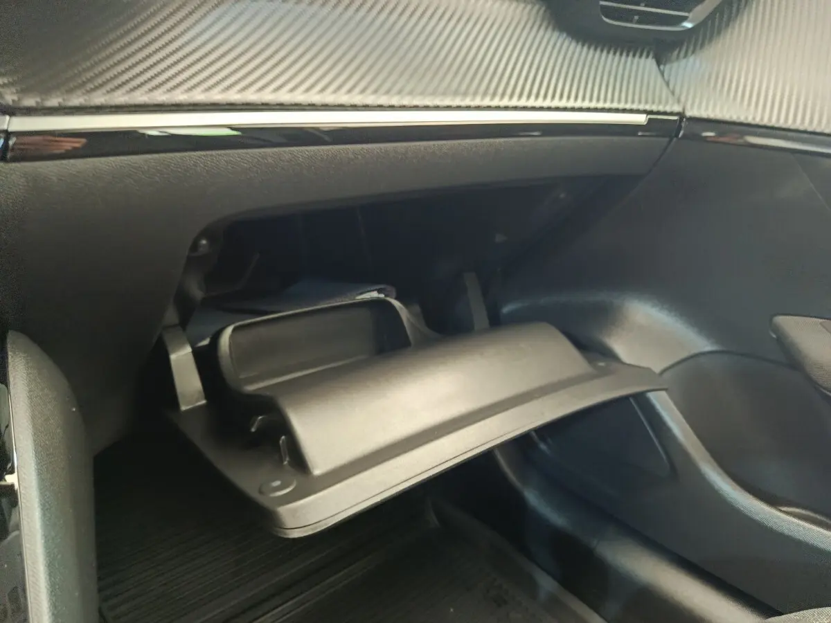 Gant de rangement ouvert côté passager dans l'habitacle noir d'une Peugeot 208 blanche, version PureTech 75 S&S Active Business.
