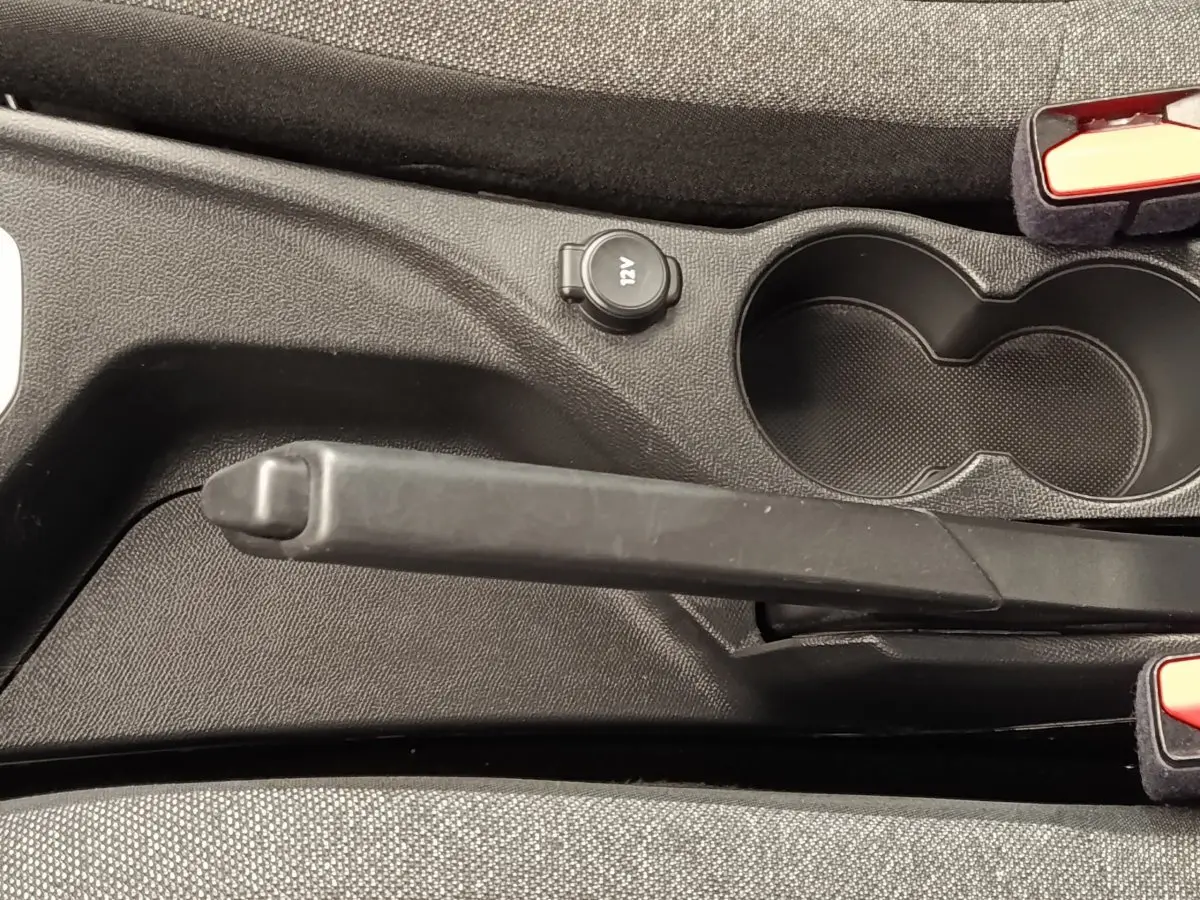 Le frein à main manuel et prise 12V visibles entre les sièges avant d'une Peugeot 208 blanche.