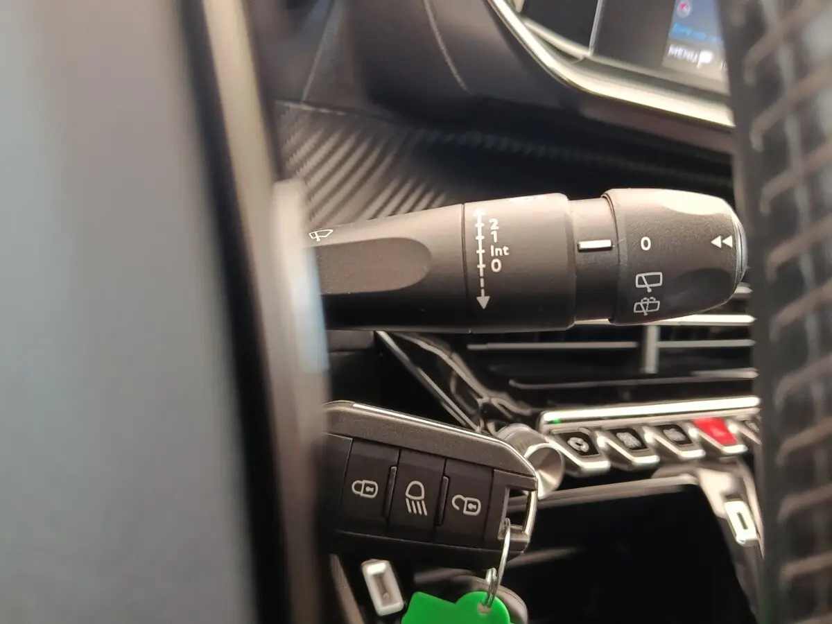Gros plan sur la manette d’essuie-glace et la clé de contact dans l’habitacle d’une Peugeot 208 blanche.