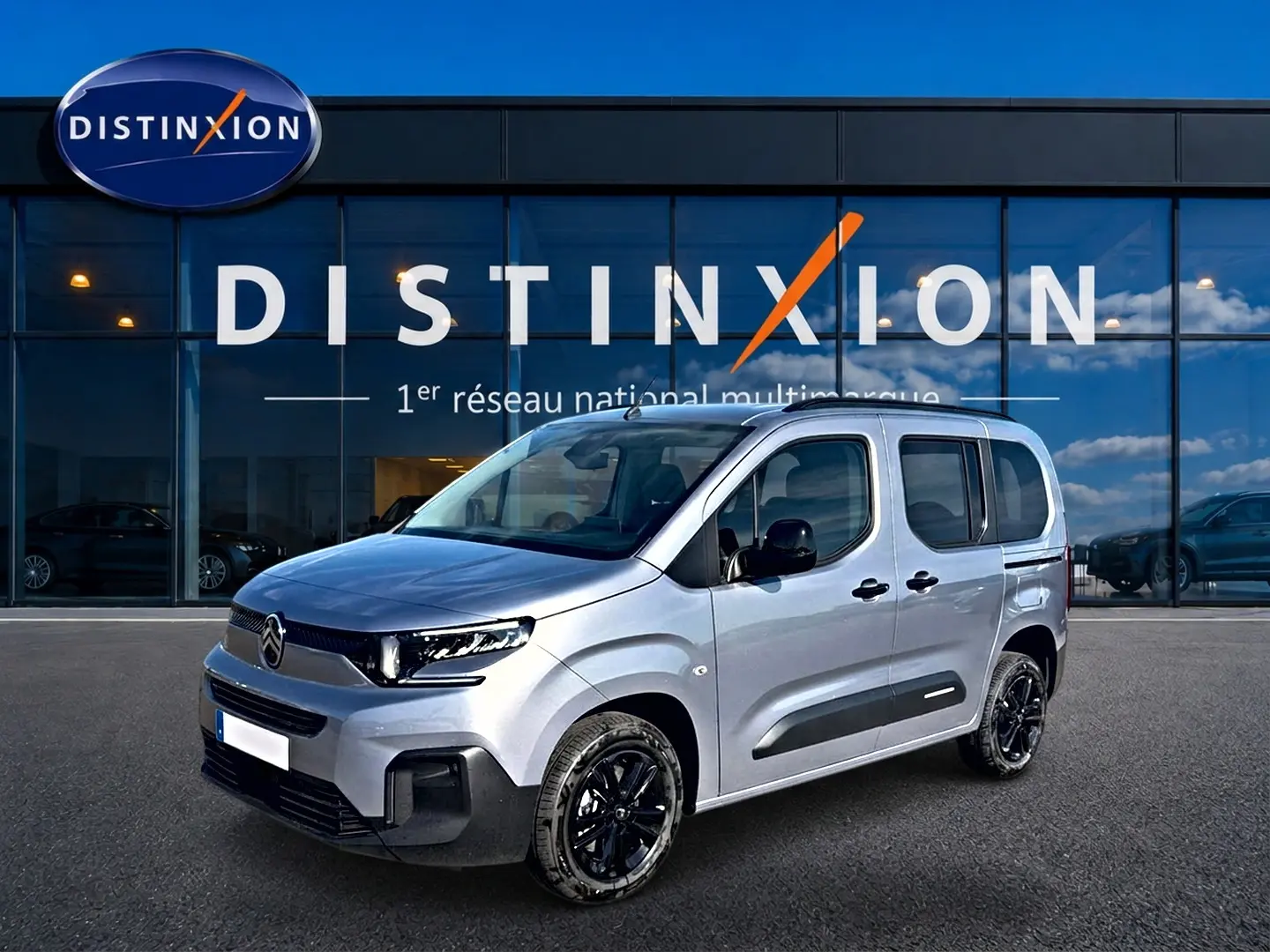 Vue 3/4 avant droit du Citroën Berlingo 2026 gris acier avec jantes noires et protections latérales noires.