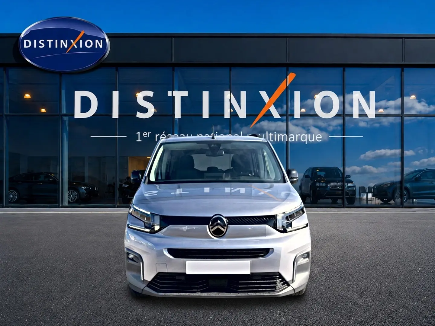 Vue de face d'un Citroën Berlingo 2026 gris acier, avec calandre moderne et phares LED devant un showroom Distinxion.