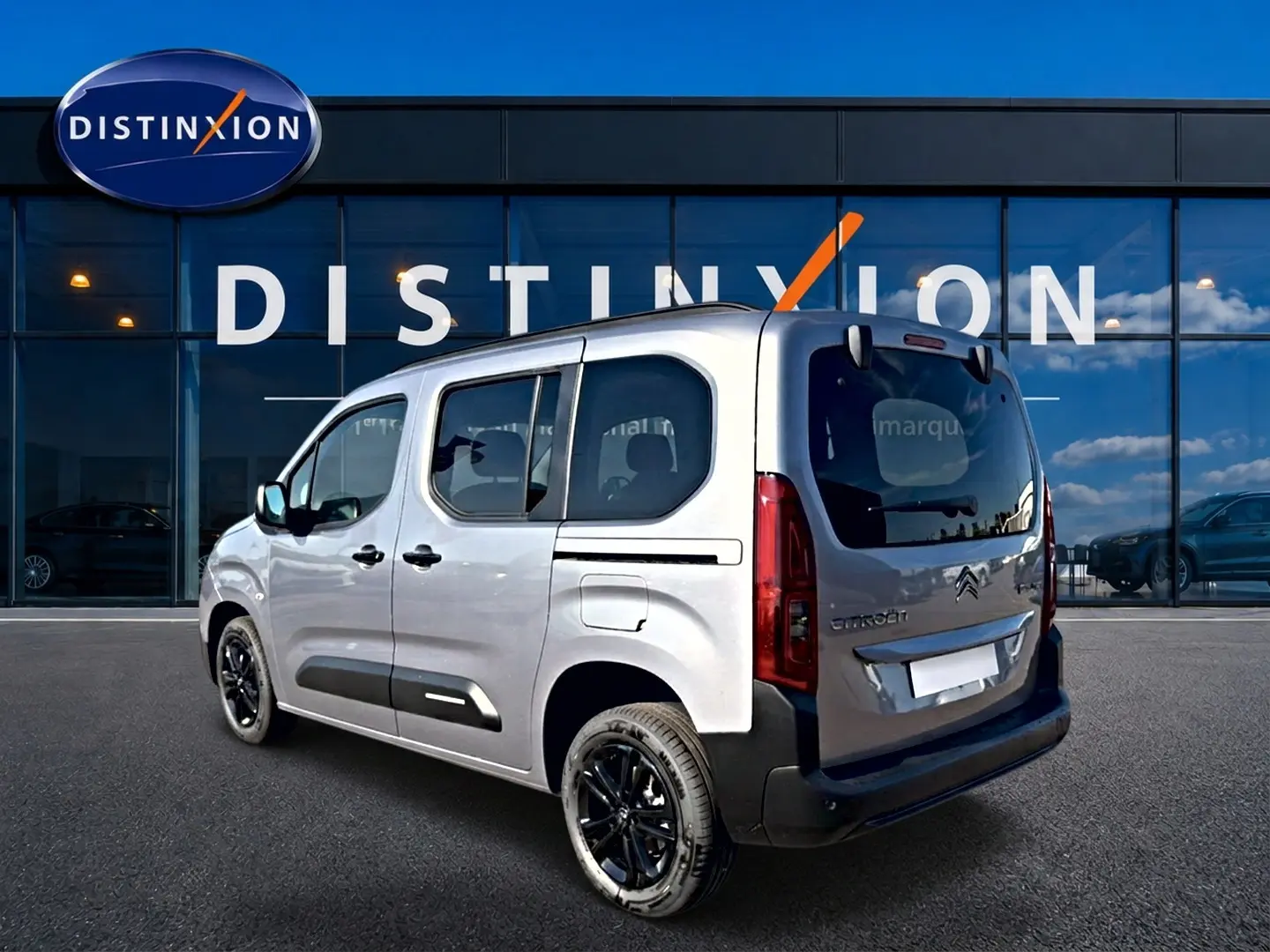 Vue 3/4 arrière droite du Citroën Berlingo gris acier avec jantes noires devant un showroom Distinxion.