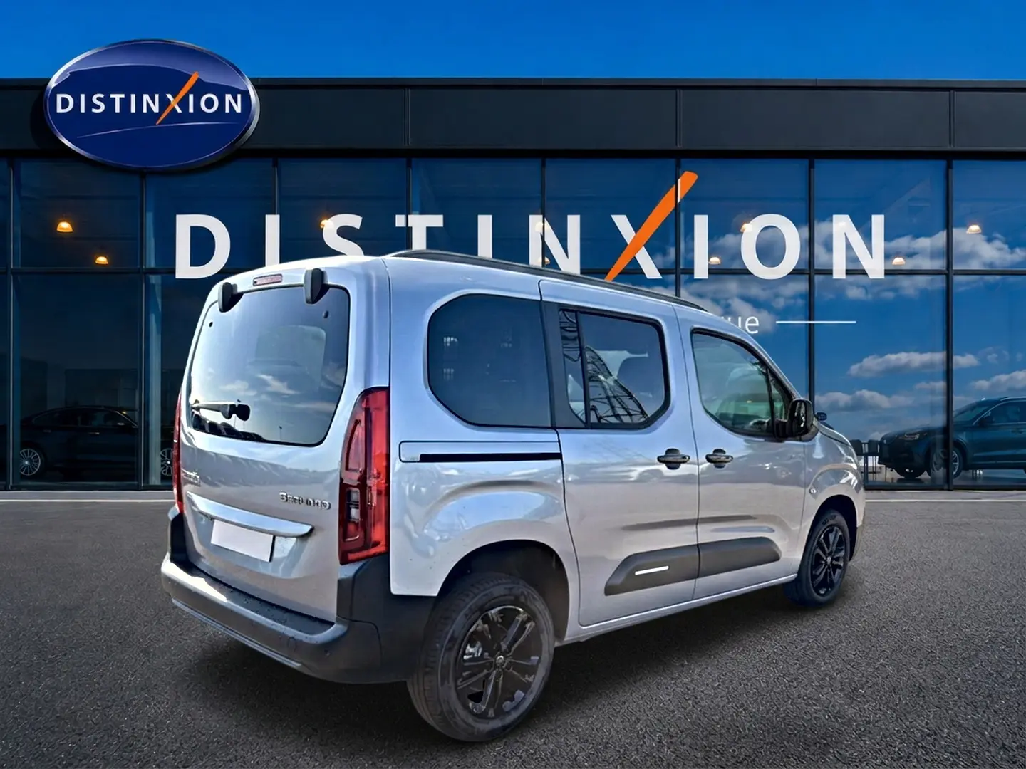 Vue 3/4 arrière droite d’un Citroën Berlingo Steel Grey 2026 avec jantes alu noires et barres de toit.