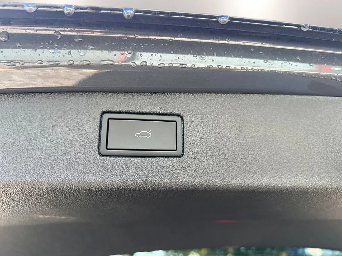 Bouton d'ouverture électrique du coffre sur le bord intérieur gris dauphin du Volkswagen Tiguan 2024.