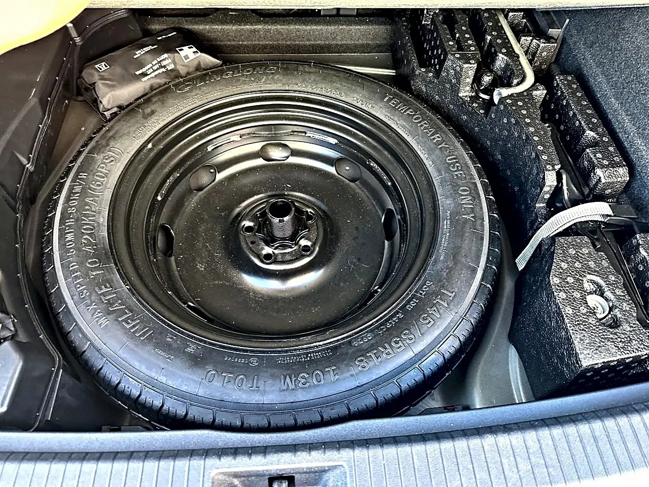 Gros plan sur la roue de secours noire dans le coffre du Volkswagen Tiguan gris dauphin 2024.